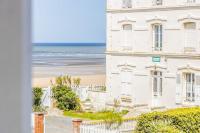 a white building with a beach in the background at Studio front de mer en centre-ville de Cabourg in Cabourg