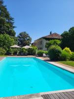 a large blue swimming pool in front of a house at Hôtel La Flambée in Bergerac