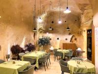 um restaurante com mesas e cadeiras numa parede de pedra em BV Quarry Matera em Matera