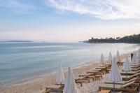 a beach with tables and white umbrellas on it at Surplage Hotel Cavalière in Le Lavandou