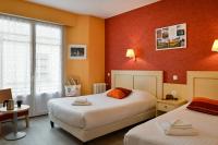 two beds in a room with orange walls at Logis Hôtel Des Châteaux De La Loire in Tours