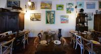 Un comedor con mesas y sillas y cuadros en la pared. en Domaine Pozzo di Mastri hôtel & spa, en Figari
