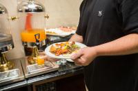un hombre sosteniendo un plato de comida en un mostrador en Blubiz Hotel Mỹ Đình (Blubiz Hotel 2), en Hanói