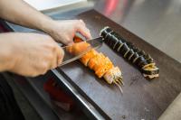 una persona cortando una zanahoria en una tabla de cortar en Blubiz Hotel Mỹ Đình (Blubiz Hotel 2), en Hanói