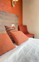 a bedroom with a bed with orange walls and a chair at Hôtel Le Belvedere in Saint-Cyprien