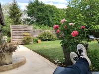 a person laying on a porch in a yard with pink roses at Le gîte de l&#39;atelier in Bergerac