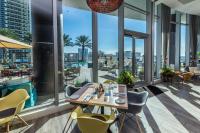 una sala da pranzo con tavolo, sedie e finestre di The Ultimate Resort - BEACHFRONT 2 BEDROOM APARTMENT WITH DIRECT OCEAN VIEW, ROOFTOP POOL, HOT TUB AND GYM a Hollywood