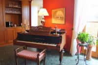 a piano in a room with a chair and a lamp at Burghotel in Rothenburg ob der Tauber