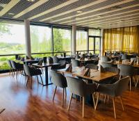 a restaurant with wooden tables and chairs and large windows at Hotelli Siuntio in Siuntio