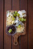 uma tábua de corte de madeira com queijo e uvas sobre ela em Amenity Penzion Horni Vestonice em Horní Věstonice