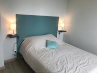 a bedroom with a bed with a blue headboard and two lamps at Bel appartement rénové, spacieux et lumineux in Bourg-en-Bresse