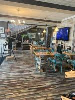 un ristorante con tavoli e sedie in legno e una scala di ArtMotel & Bistro a Haţeg