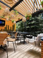 Un patio con mesas y sillas bajo una pérgola de madera. en Cabañas Boutiques TinyChillHouse, en Mineral del Chico