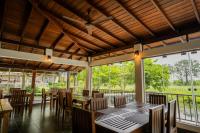 a dining room with tables and chairs and large windows at Malala Retreat in Hambantota