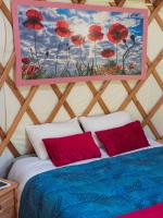 a room with a bed with red pillows and a painting at Yourtissimo in Laprugne