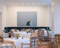 een kamer met tafels en stoelen en een foto van een man bij The Peninsula Beverly Hills in Los Angeles