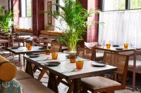 um restaurante com mesas de madeira, cadeiras e plantas em The Hoxton, Berlin em Berlim