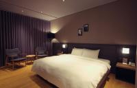 a bedroom with a large white bed and chairs at Chiayi Guanzhi Hotel in Chiayi City