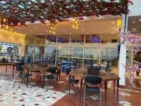 een restaurant met houten tafels, stoelen en bloemen bij منتجع شاطئ النخيل in Half Moon Bay