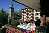 a table on a balcony with a view of a building at Grand Hotel Zermatterhof in Zermatt