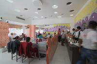 eine Gruppe von Menschen, die an Tischen in einem Restaurant sitzen in der Unterkunft Hotel Samrat International in Mount Ābu