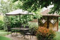 a table and chairs with an umbrella and a gazebo at Zagorod Hotel in Girka Polonka