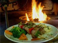 ein Teller mit Fleisch und Gemüse vor einem Feuer in der Unterkunft Gondwana Canyon Roadhouse in Stamprivier