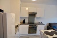 a small kitchen with white cabinets and a table at Appartement dans résidence au calme in Bayonne