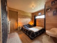 a bedroom with a bed in a room with wooden walls at Le Repère des Quatre Dubois in Le Tholy