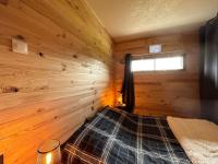 a room with a bed in a wooden cabin at Le Repère des Quatre Dubois in Le Tholy
