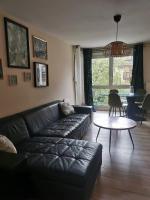 a living room with a black leather couch and a table at appartement cosy à 10 min du centre de Strasbourg in Strasbourg