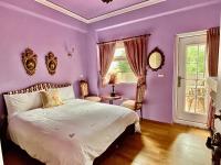 a purple bedroom with a bed and a window at England Castle B&amp;B in Wujie