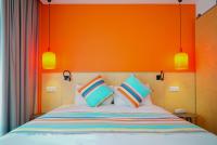 a bed with an orange headboard with colorful pillows at La Regence in Courbevoie