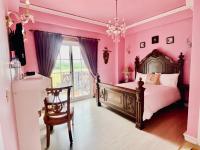 a pink bedroom with a bed and a chair at England Castle B&amp;B in Wujie
