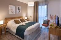 a bedroom with a large bed and a chair at DOMITYS LES CERNEAUX in Hazebrouck