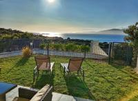 a yard with two chairs and a table and the ocean at Les Rivages de Stagnola Appartement T3 vue mer et montagne plage 200m climatisé in Pietrosella