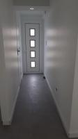 a hallway with white walls and a door with windows at REZ DE JARDIN AU COEUR DES PYRENEES in Agos-Vidalos