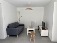 a living room with a couch and a tv and a stool at REZ DE JARDIN AU COEUR DES PYRENEES in Agos-Vidalos