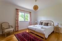 a bedroom with a bed and a chair and a window at Villa des Sables in Lège-Cap-Ferret