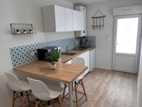 a kitchen with a wooden table and white cabinets at Studio cosy avec terrasse, proche Chantiers et Airbus in Saint-Nazaire