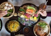 Una mesa llena de tazones de comida con gente sosteniendo palillos. en City Centre Rotana Doha, en Doha