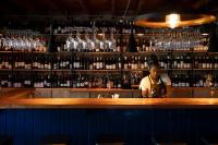 a man behind a bar with bottles of wine at Tarry-Stone Cottages in Dullstroom