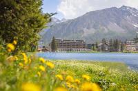 a view of a lake with a building and mountains at AVES Hotel&amp;Apartment Arosa in Arosa