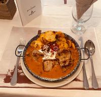 バヤにあるTanyacsárda Panzióのテーブルの上に肉とジャガイモのスープが入ったボウル