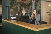 a woman sitting at a counter talking on a cell phone at Hotel Rhönkitz in Bad Kissingen