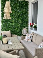 a patio with a couch and a table in front of a green wall at Apartman SUN in Inđija