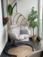 a rattan swing chair in a room with a rug at Apartman SUN in Inđija