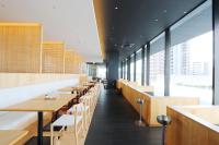 Un restaurante con mesas y sillas de madera y grandes ventanales. en Spa & Hotel Suishun Matsuiyamate, en Kioto