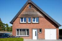 a red brick house with two white garage doors at Apartment with a view and parking in Brecht