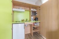 a small kitchen with green walls and wooden cabinets at Appart’City Confort Tours in Tours